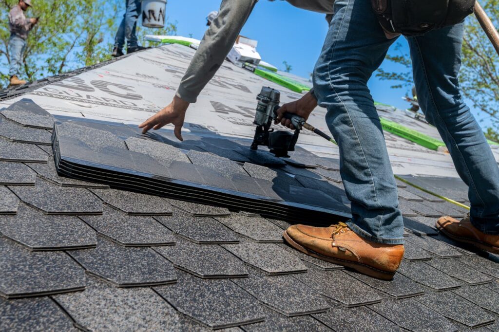pexels-photo-33404248 Roofer using nail gun for shingle installation on residential roof.